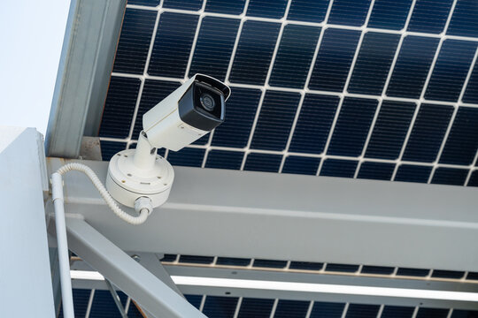 Solar powered security camera mounted under photovoltaic panel grid system. Renewable green energy, smart city infrastructure, sustainable technology, surveillance, autonomous urban safety monitoring