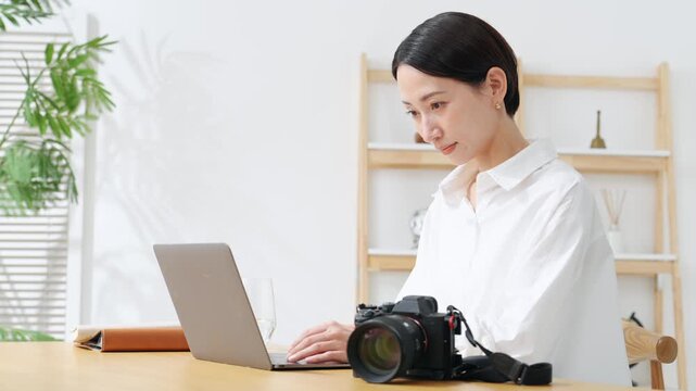 カメラとノートパソコンを使う女性。写真、編集、撮影、カメラマン、カメラ女子、現像、オークション、出品