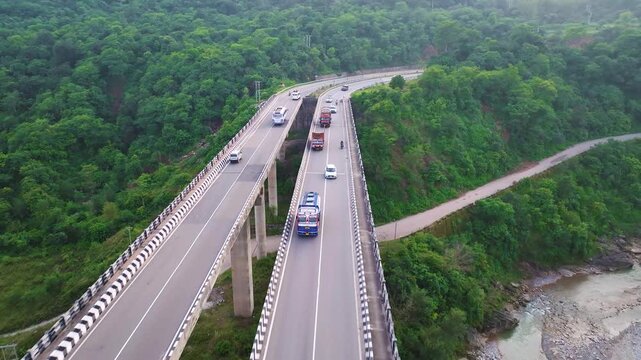 Aerial tracking shot of cargo trucks crossing elevated express way bridge in North India