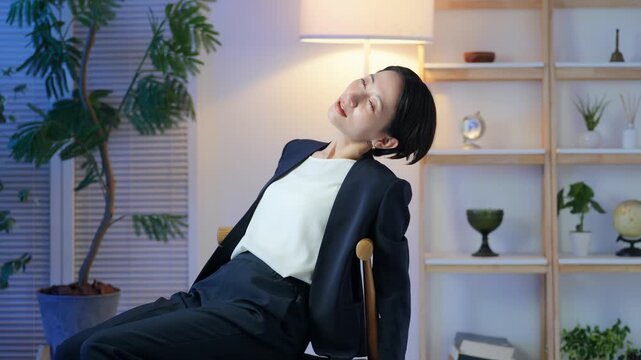 室内でぐったりする女性ビジネスパーソン。疲労、疲れ、残業、ストレス、放心、落ち込む、過労、仕事、夜