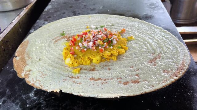 Indian chef preparing masala dosa crepe on hot tawa 4k video footage