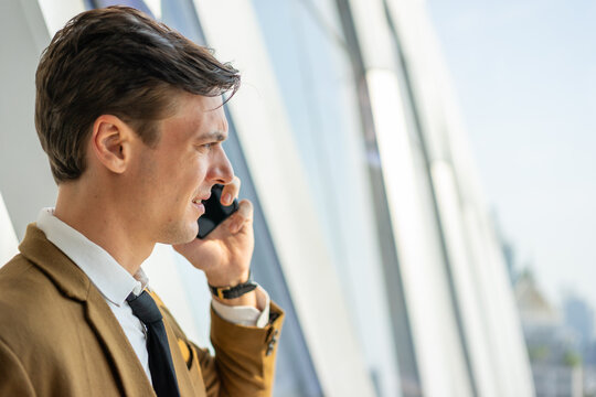 Businessman on mobile phone call by window in city office