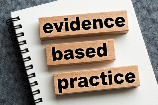 Wooden blocks with text evidence based practice lie on spiral notebook. Close up view of concept for scientific research, medical methodology, pro learning. Business strategy, academic study