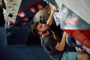 Male climber working out on artificial wall in health club. © Drazen