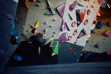 Back view of climber during bouldering workout in health club. © Drazen