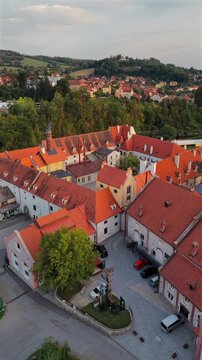 Vertical aerial drone shot over the old brewery with its tall malthouse chimney and red rooftops in Česk&yacute; Krumlov, Czech Republic, with the town behind