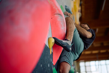 Close up of boulderer climbing up the wall while practicing indoors. © Drazen