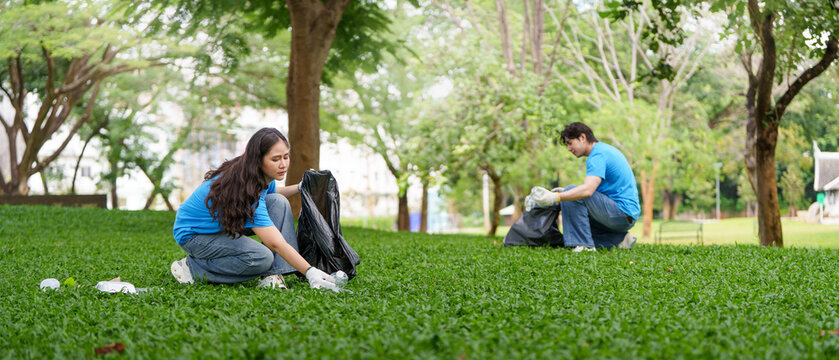 Asian volunteers picking up plastic litter in green park for environmental cleanup