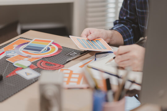 Designer working with color palettes, layout templates, and creative design tools on a desk while planning branding and graphic design projects in a modern office.
