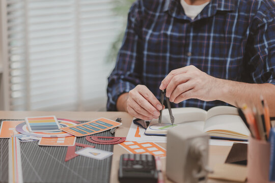 Designer working with color palettes, layout templates, and creative design tools on a desk while planning branding and graphic design projects in a modern office.