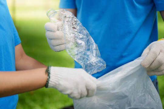 Cropped hands placing crushed plastic bottle into recycling bag for waste management