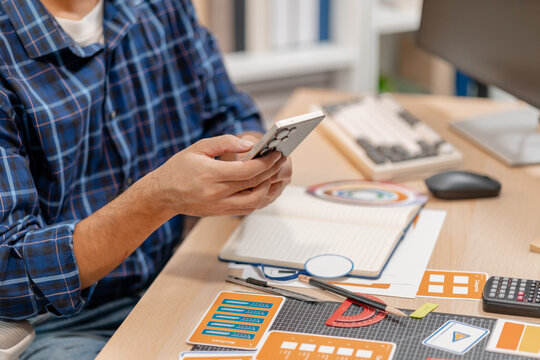 Designer working with color palettes, layout templates, and creative design tools on a desk while planning branding and graphic design projects in a modern office.