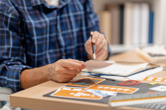 Designer working with color palettes, layout templates, and creative design tools on a desk while planning branding and graphic design projects in a modern office.