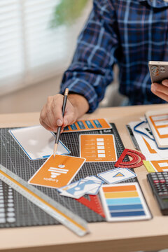 Designer working with color palettes, layout templates, and creative design tools on a desk while planning branding and graphic design projects in a modern office.
