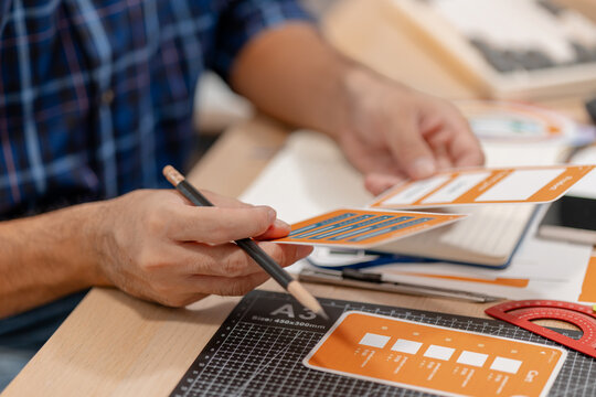 Designer arranging color swatches, layout samples, and branding materials on a creative workspace while planning a visual identity project with notebooks and design tools.