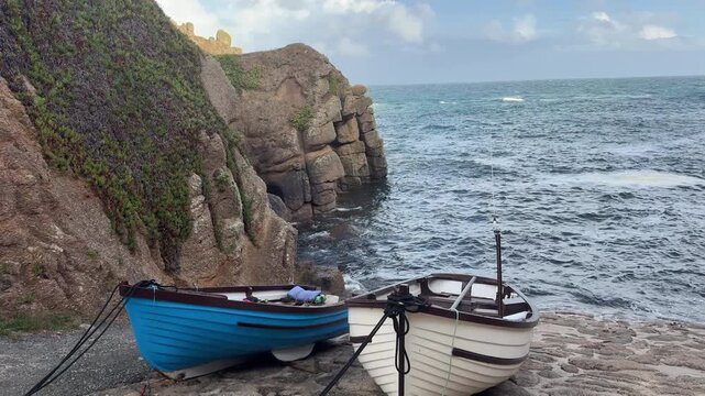 A small Cornish fishing bay with boats on the slip way. A tourist area and pretty landscape on the ocean in England UK 4K
