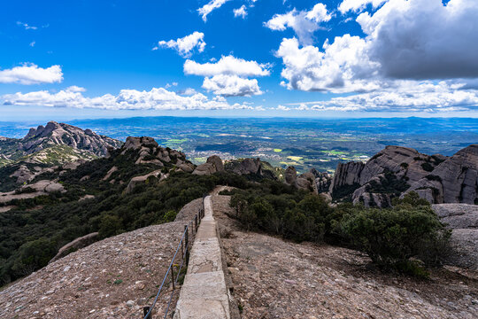 Stunning anorama view of round rocks on the hiking path on top of Sant Jeroni mountain with Catalan Central Depression in background, in Montserrat near Barcelona in spring, Catalonia, Spain