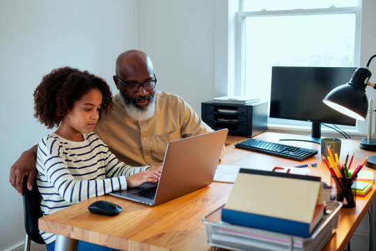 African American senior man guiding child using laptop at desk, supporting online learning and digital skills at home. Ideal for education, parenting, mentoring, technology campaigns