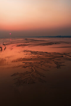 Drone image of tidal tree at the sunrise time. The patterns are carved into the mudflats by the high speed ebb and flow of tidal bores.