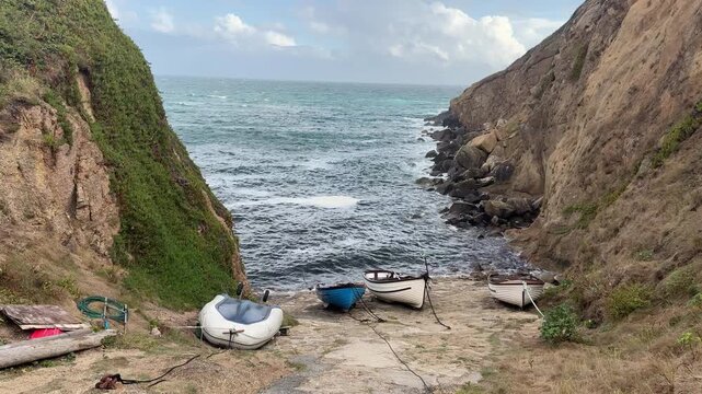 A small Cornish fishing bay with boats on the slip way. A tourist area and pretty landscape on the ocean in England UK 4K