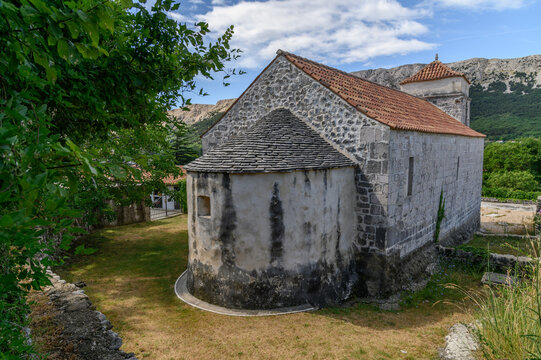 Rear view of St Lucia church in Jurandvor with semicircular apse under a stone slab roof and bell tower, Ba&scaron;ka, Krk island, Croatia