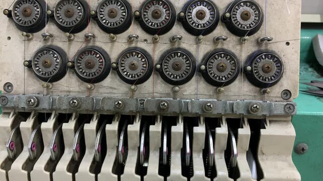 Close up of a multi thread textile machine featuring tension control assemblies used in industrial sewing and embroidery operations