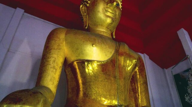 Sacred golden Buddha statues and colorful traditional giant guardian sculptures inside a historic Buddhist temple sanctuary.