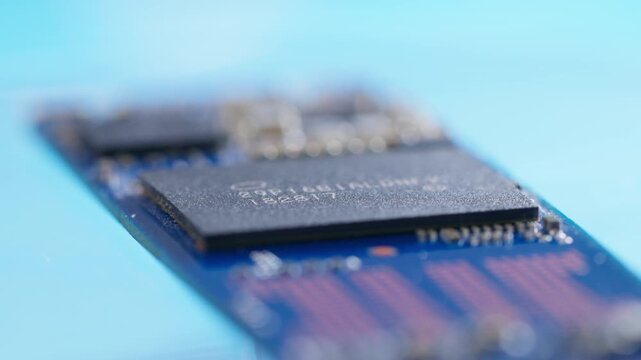 rotating solid-state drive SSD computer hardware storage microchip showing flash memory grid and circuitry layout on a blue background as a conceptual backdrop for data storage cloud 