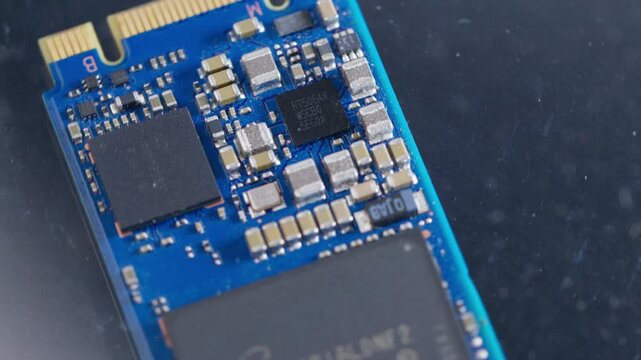rotating solid-state drive SSD computer hardware storage microchip showing flash memory grid and circuitry layout on a blue background as a conceptual backdrop for data storage cloud 