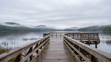 Fototapeta premium Cloudy Lakeside Boardwalk with Misty Mountains for Travel