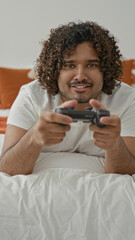 Man holding controller on bedroom bed, hands on joystick and smiling while playing games  playful leisure. © Krakenimages.com