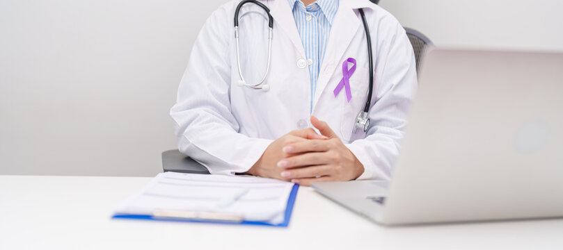 doctor using laptop and report notes on notebook. purple ribbon for concept of Violence, Pancreatic, Esophageal, Testicular cancer, Alzheimer, Epilepsy, Lupus, Crohn and Fibromyalgia. Awareness month