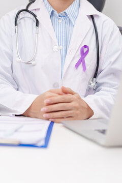 doctor using laptop and report notes on notebook. purple ribbon for concept of Violence, Pancreatic, Esophageal, Testicular cancer, Alzheimer, Epilepsy, Lupus, Crohn and Fibromyalgia. Awareness month