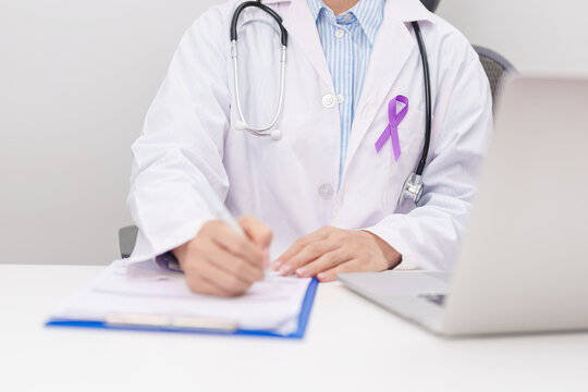doctor using laptop and report notes on notebook. purple ribbon for concept of Violence, Pancreatic, Esophageal, Testicular cancer, Alzheimer, Epilepsy, Lupus, Crohn and Fibromyalgia. Awareness month