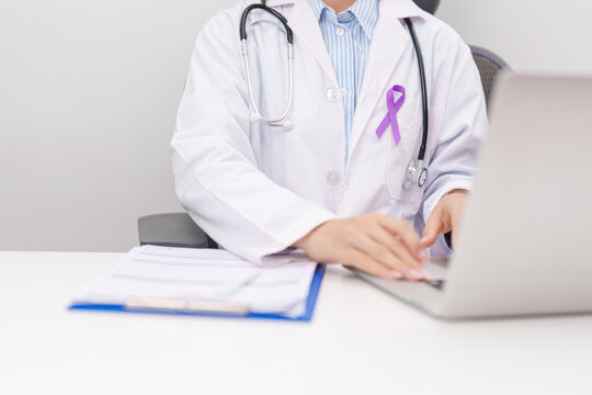 doctor using laptop and report notes on notebook. purple ribbon for concept of Violence, Pancreatic, Esophageal, Testicular cancer, Alzheimer, Epilepsy, Lupus, Crohn and Fibromyalgia. Awareness month