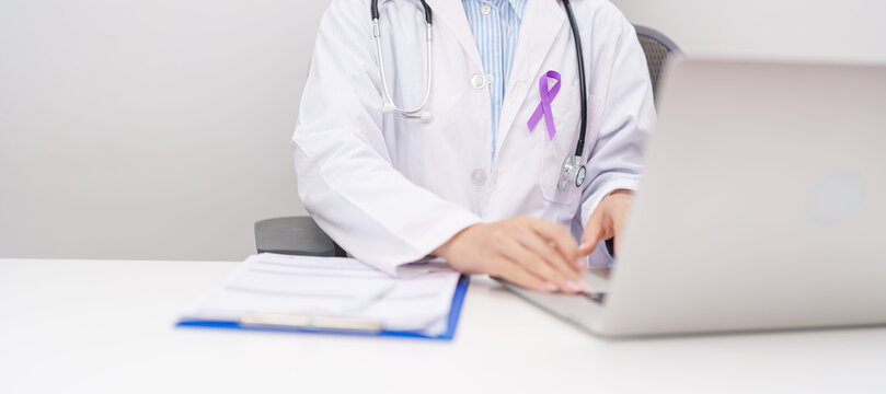 doctor using laptop and report notes on notebook. purple ribbon for concept of Violence, Pancreatic, Esophageal, Testicular cancer, Alzheimer, Epilepsy, Lupus, Crohn and Fibromyalgia. Awareness month