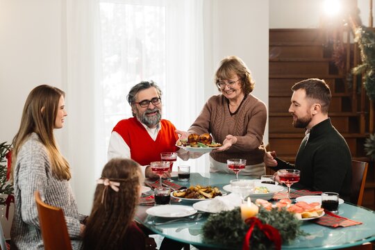 Grandmother serving christmas dinner to happy family