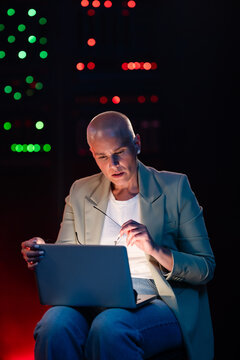 Bald woman working with laptop in server room