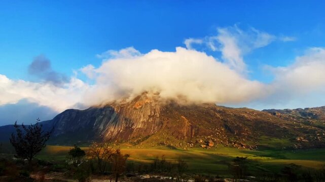 Time lapse of dawn clouds rolling over a rocky Mount Mulanje summit in Malawi as warm early light reaches the slopes and the peak disappears into cloud.