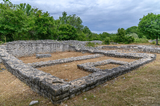 Low stone walls of an excavated Roman house on an Adriatic island under a cloudy summer sky