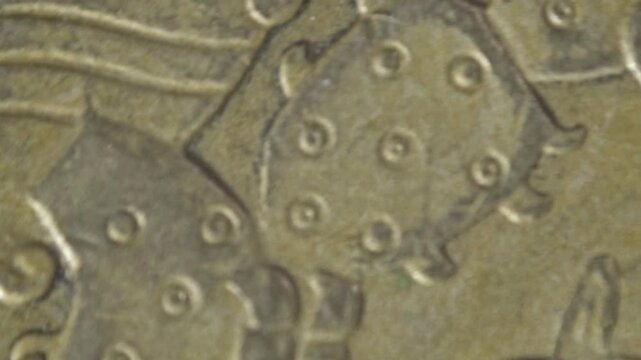 Close up spinning shot of a Mexican coin showing an eagle holding a snake on its surface. Detailed engraving highlights the symbolic design and metallic texture.