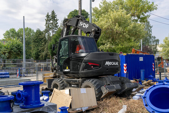 Nancy, France - August 1st 2026 : View of a 15-tonne black compact wheeled excavator Mecalac 15MWR on a construction site for work on the drinking water network.