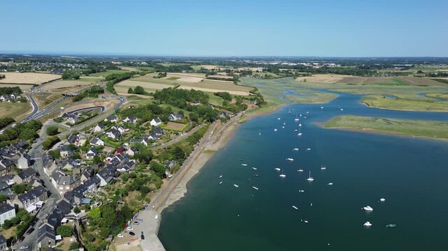 Aerial drone view of Saint-Jean in Brittany, France, overlooking the Rance estuary near Pont Saint-Hubert. The coastal village, boats, tidal wetlands, countryside and surrounding fields are visible fr