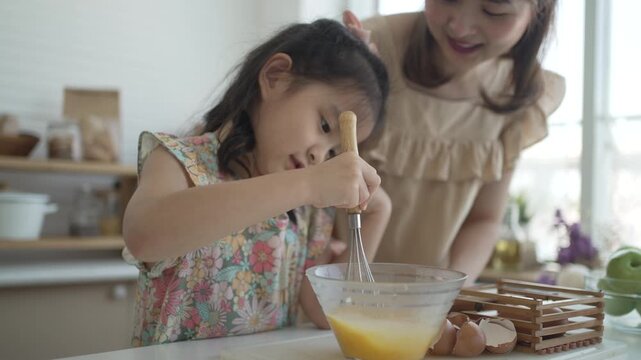 Close-up of daughter whisking egg mixture as mother watches