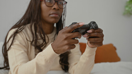 Woman gripping game controller while seated on bed in bedroom, hands visible on joystick and buttons  concentration. © Krakenimages.com
