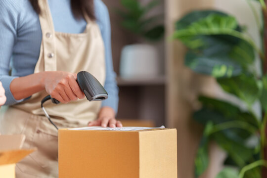 Small business owner scanning barcode on parcel box with scanner for online order tracking