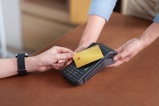 Customer paying with contactless credit card on POS terminal in small business store