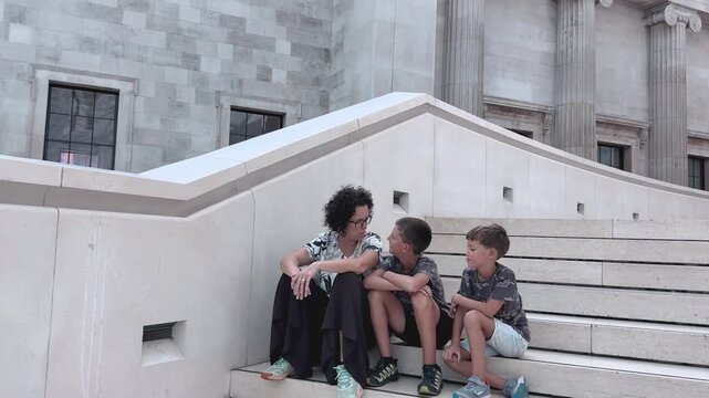 Mother and Two Sons Resting Together on Stone Steps in London