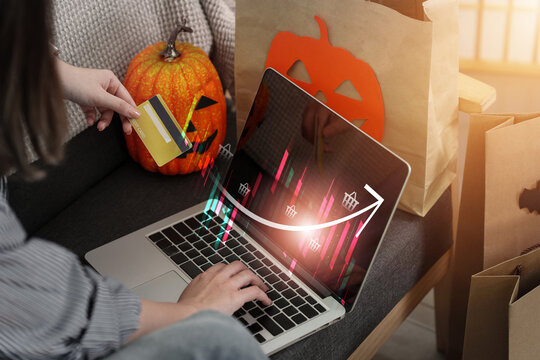 Woman holding credit card and using laptop for Halloween online shopping