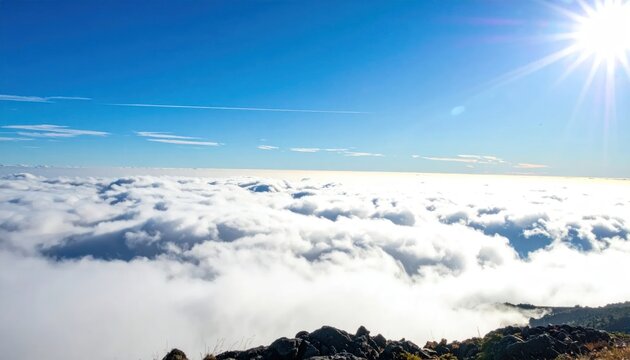 Aerial view of white clouds from mountain peak under sun